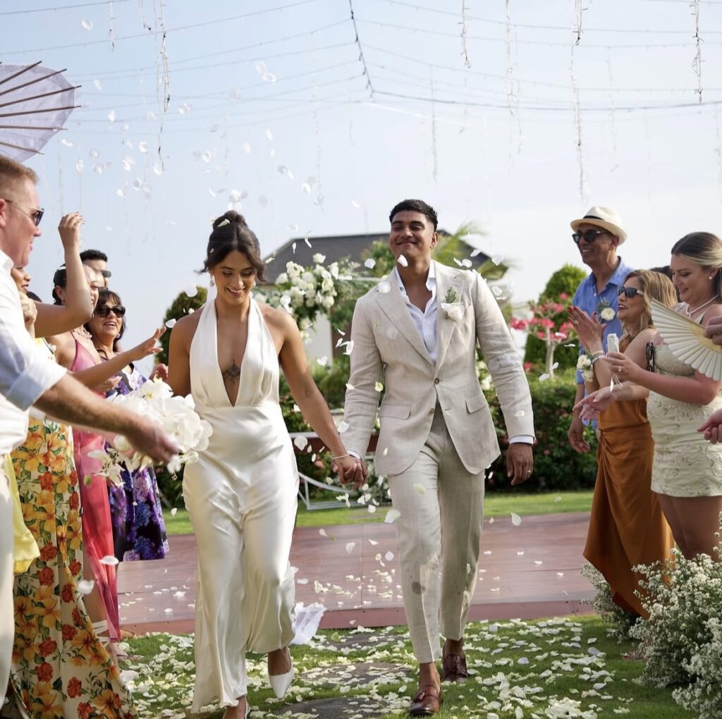 Jess and Ameer walking down the aisle as newlyweds.