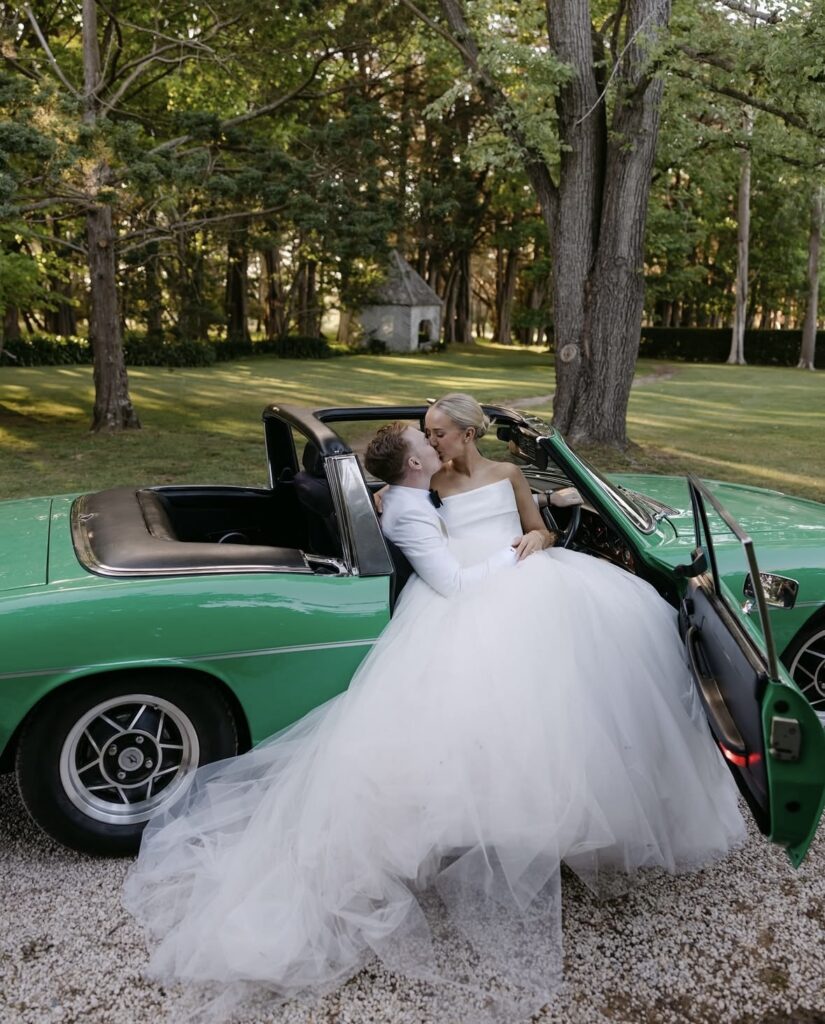 Georgia and Nick kissing in a vintage car post-wedding ceremony.